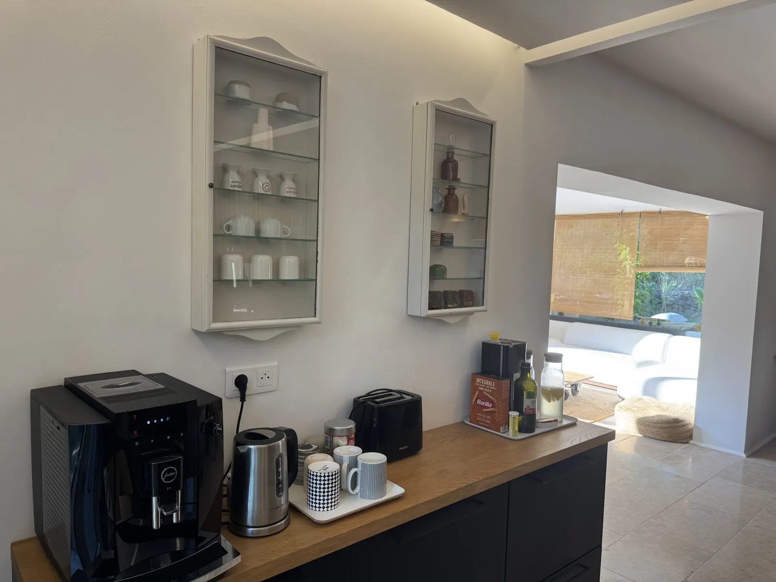 Le coin petit déjeuner de la cuisine de Baraccò Argia, machine à café Jura, bouilloire et vaisselle dans les vitrines murales