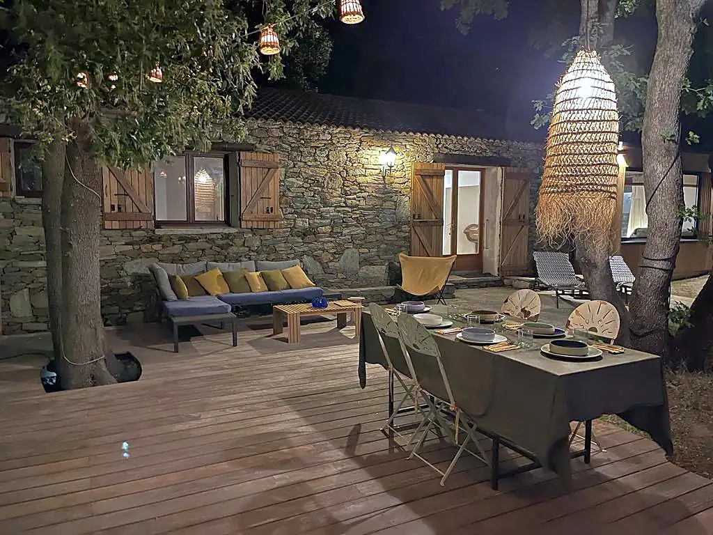 La terrasse de Baraccò Argia le soir, table dressée sous les guirlandes, façade de pierre éclairée